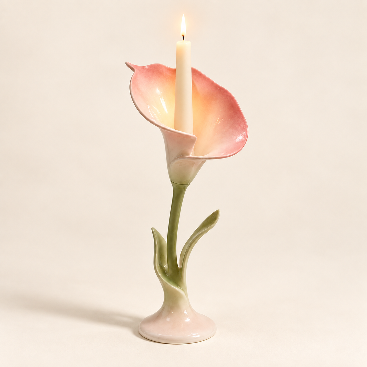 Lit ceramic calla lily candle holder with a taper candle glowing inside the blush pink bloom.